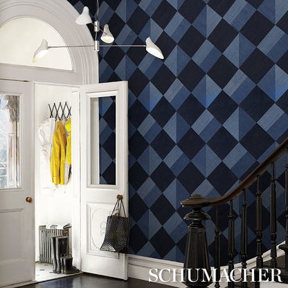 Blue diamond wallpaper in navy tones, white door, yellow jacket, black bag, modern light, dark wood staircase.