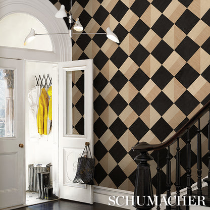 Harlequin black and beige diamond wallpaper in an entry hall, with white doors, a staircase railing, and a coat.