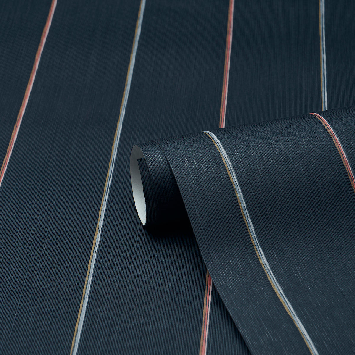 Dark navy fabric with thin orange, blue and beige stripes; woven texture, rolled edge.