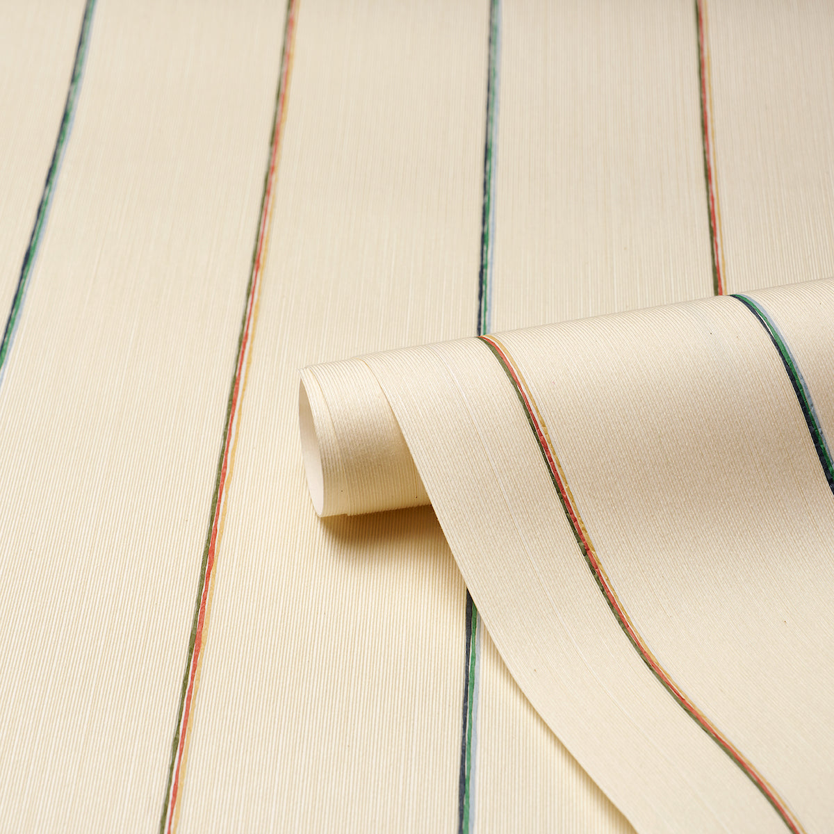 Cream textured wallpaper with narrow multicolored stripes (blue, green, brown), rolled at the edge.