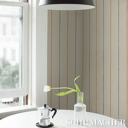 Stainless moka pot & white tulip in a glass vase on a white table, striped beige walls and daylight create minimalist vibe.