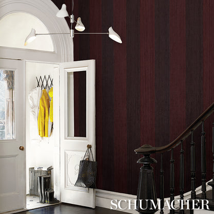 White doors with an arched transom beside burgundy striped wallpaper; wardrobe shows yellow coat and black handbag, staircase railing nearby.