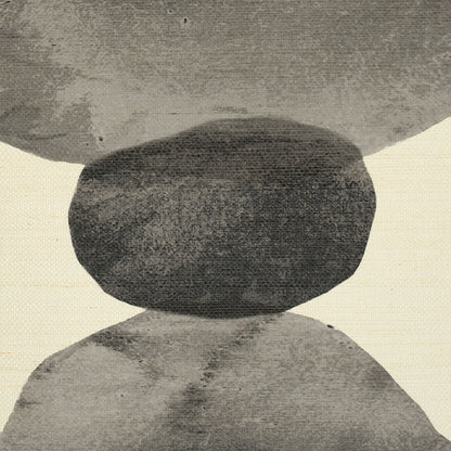 Monochrome balancing stones sculpture: dark top rock perched on a larger light rock with a textured backdrop.