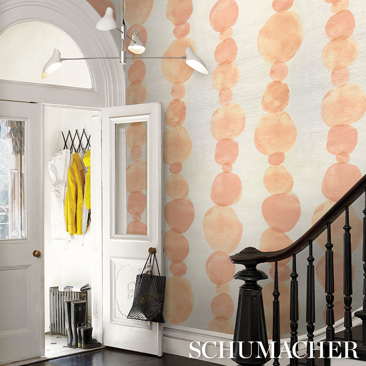 Entryway with peach circular dot wallpaper, white doors, dark wood staircase balustrade and modern track lighting.