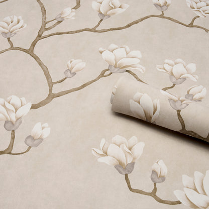 Neutral wallpaper with ivory magnolia blossoms on brown branches, rolled edge exposing beige background.