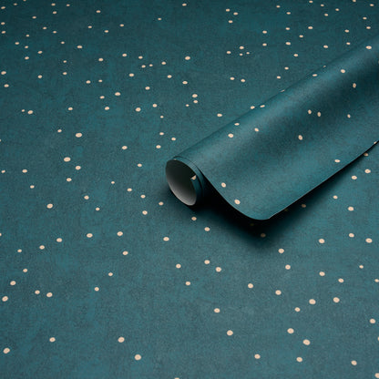 Teal wrapping paper with small white polka dots, partially rolled to reveal a curled edge.