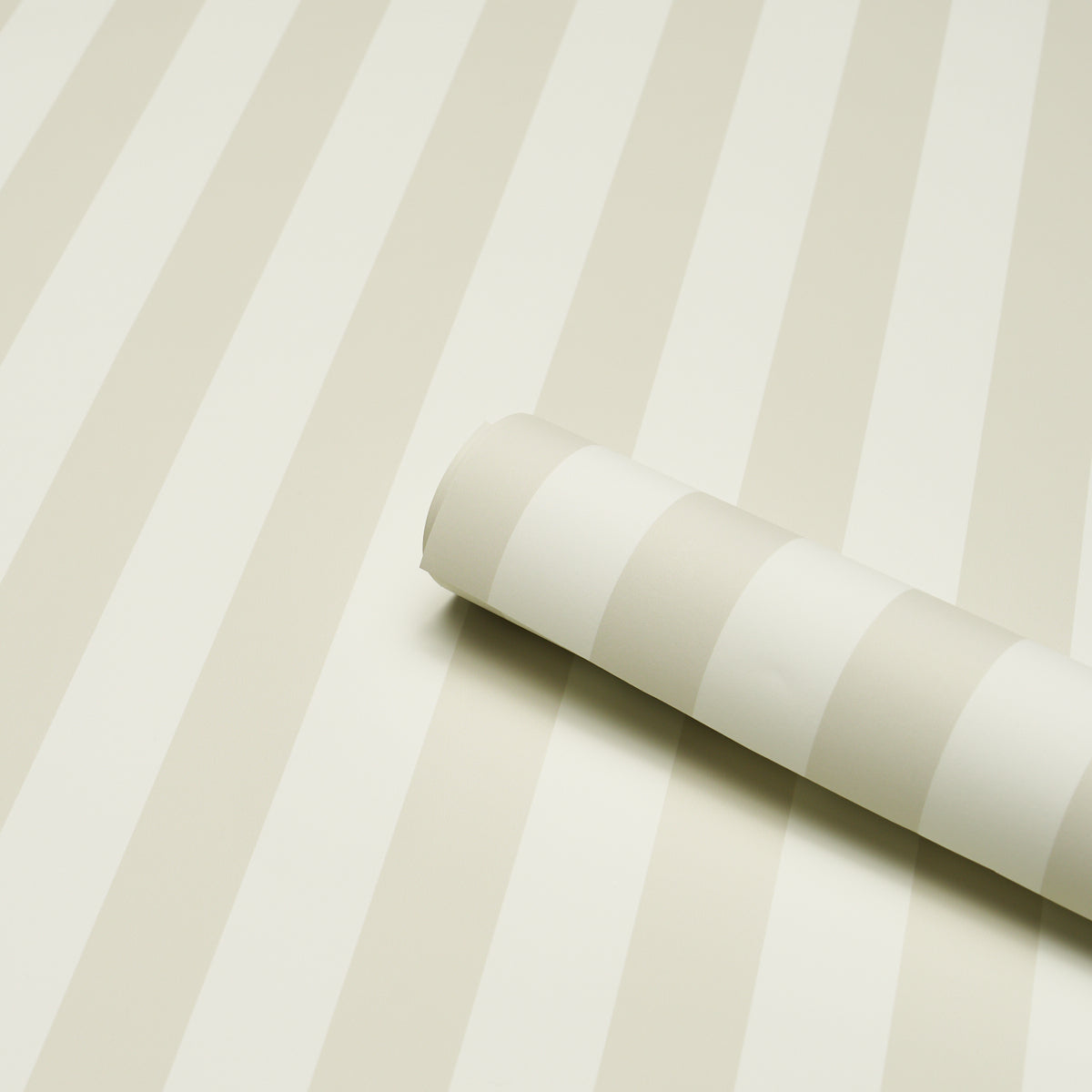 Rolled wallpaper sample with ivory and cream stripes on a beige striped wallpaper backdrop.