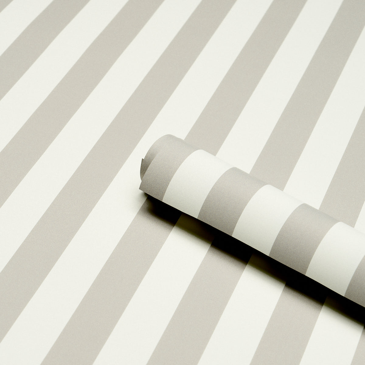 Gray and white striped wallpaper roll on a matching striped surface.