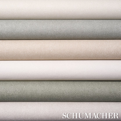 Stack of textured leather rolls in neutral shades (cream, beige, taupe, gray, sage) with pebble-grain finish.