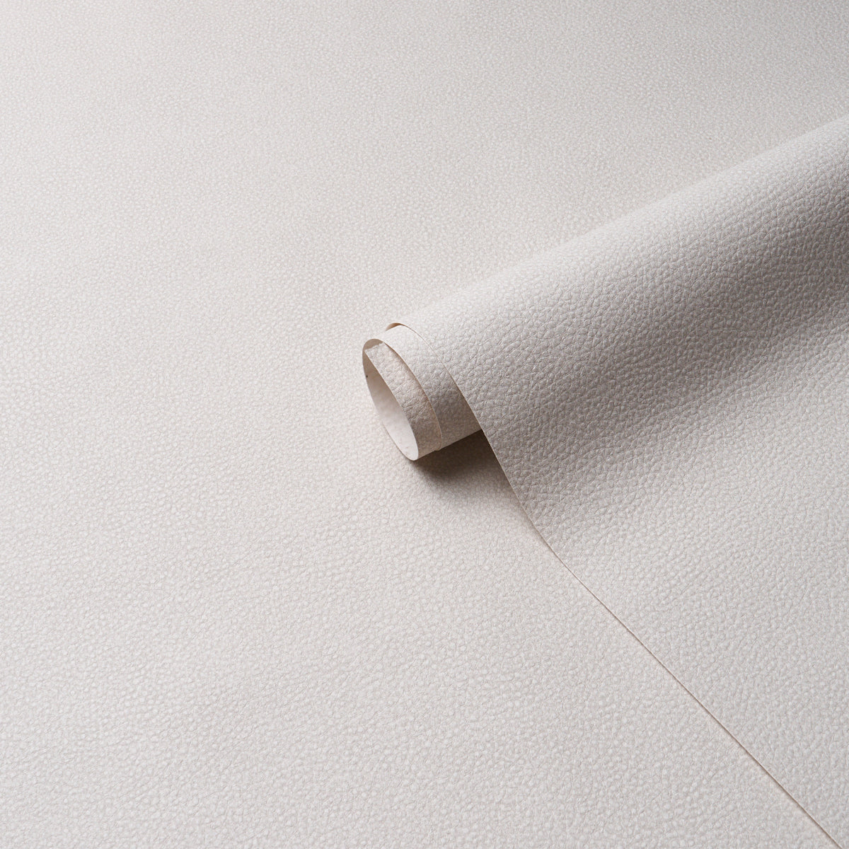 Beige pebbled leather sheet rolled at the edge, textured upholstery leather suitable for crafts.