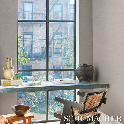 Industrial-style home office by a large grid window; gray desk with ceramic vase, dark pot, books, and a woven-back chair.