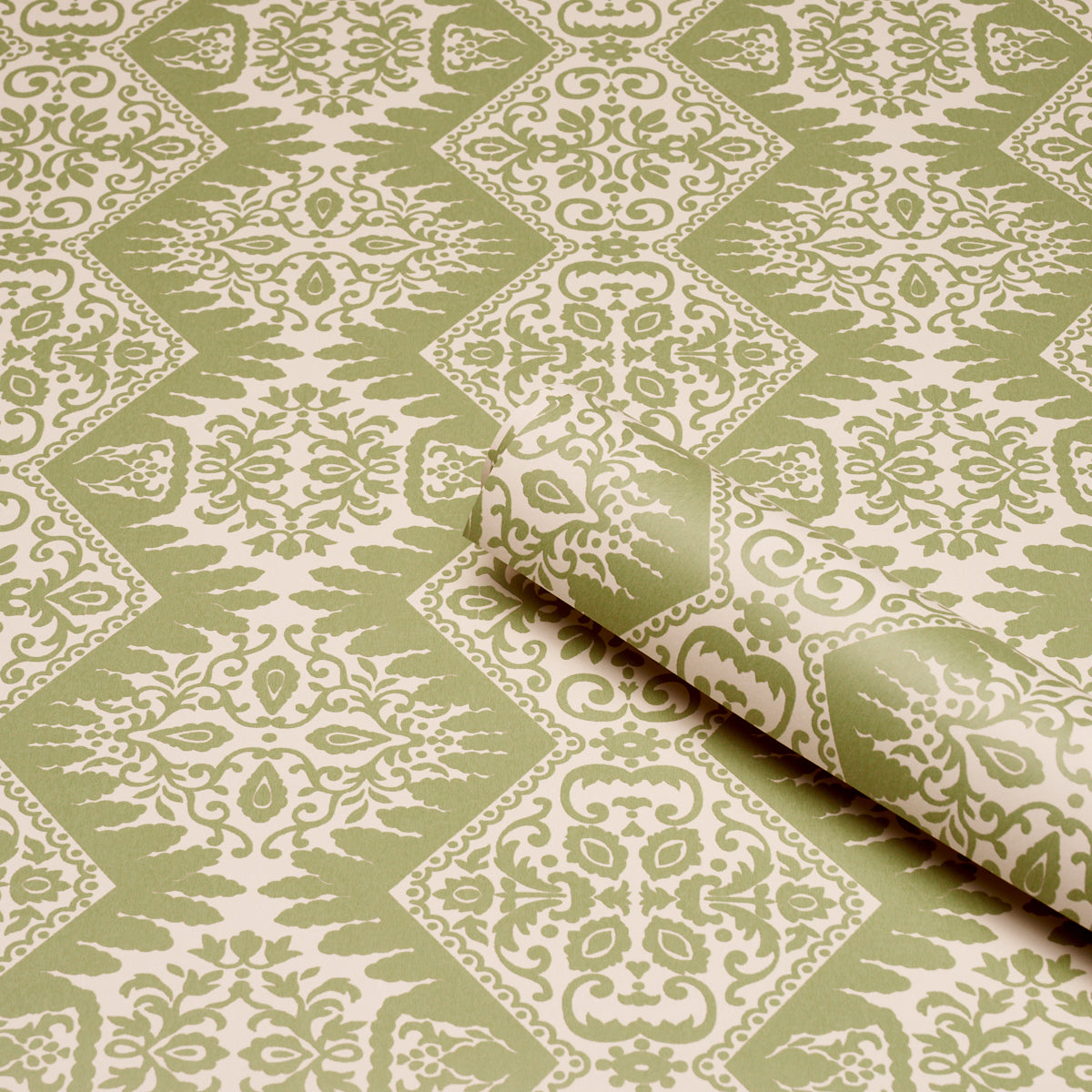 Olive green and cream damask wallpaper with repeating diamonds; rolled corner shows subtle texture.