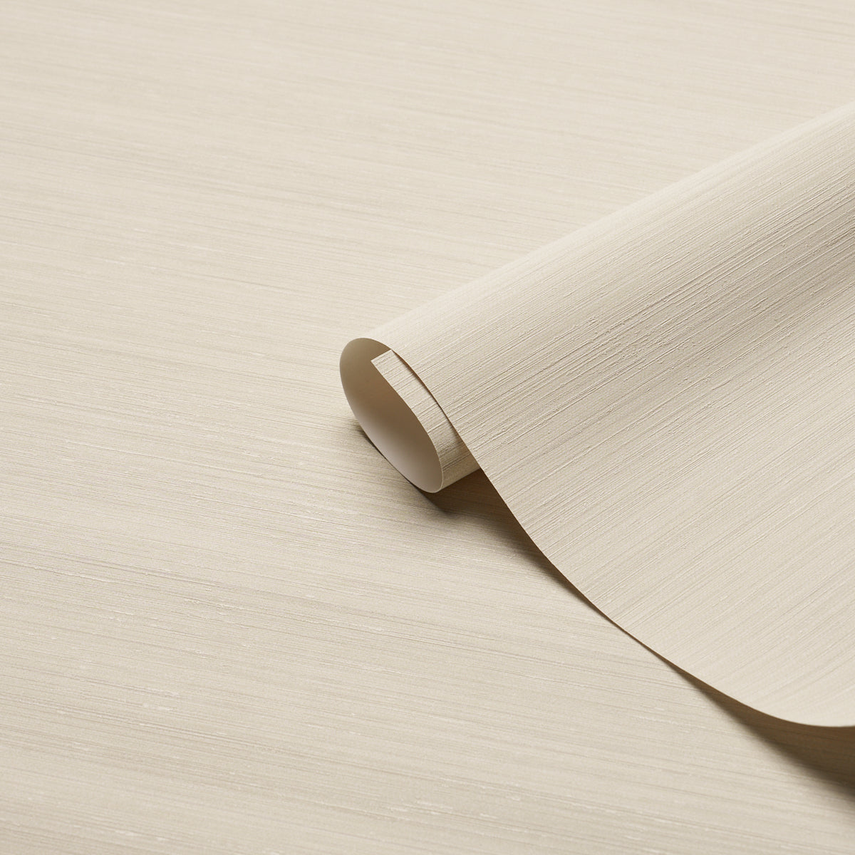 Beige textured wallpaper roll curling at the edge on a pale wood surface.