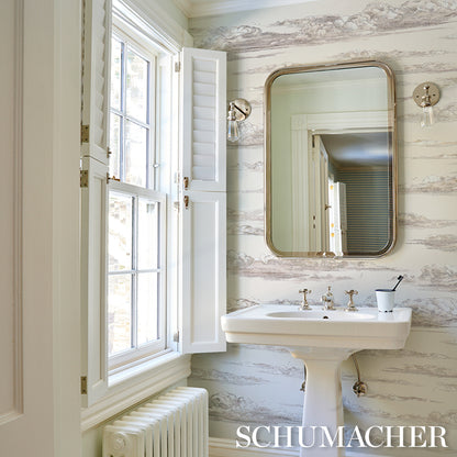 Bright vintage bathroom with pedestal sink, brass rounded mirror, white window shutters, striped wallpaper, toothbrush cup.