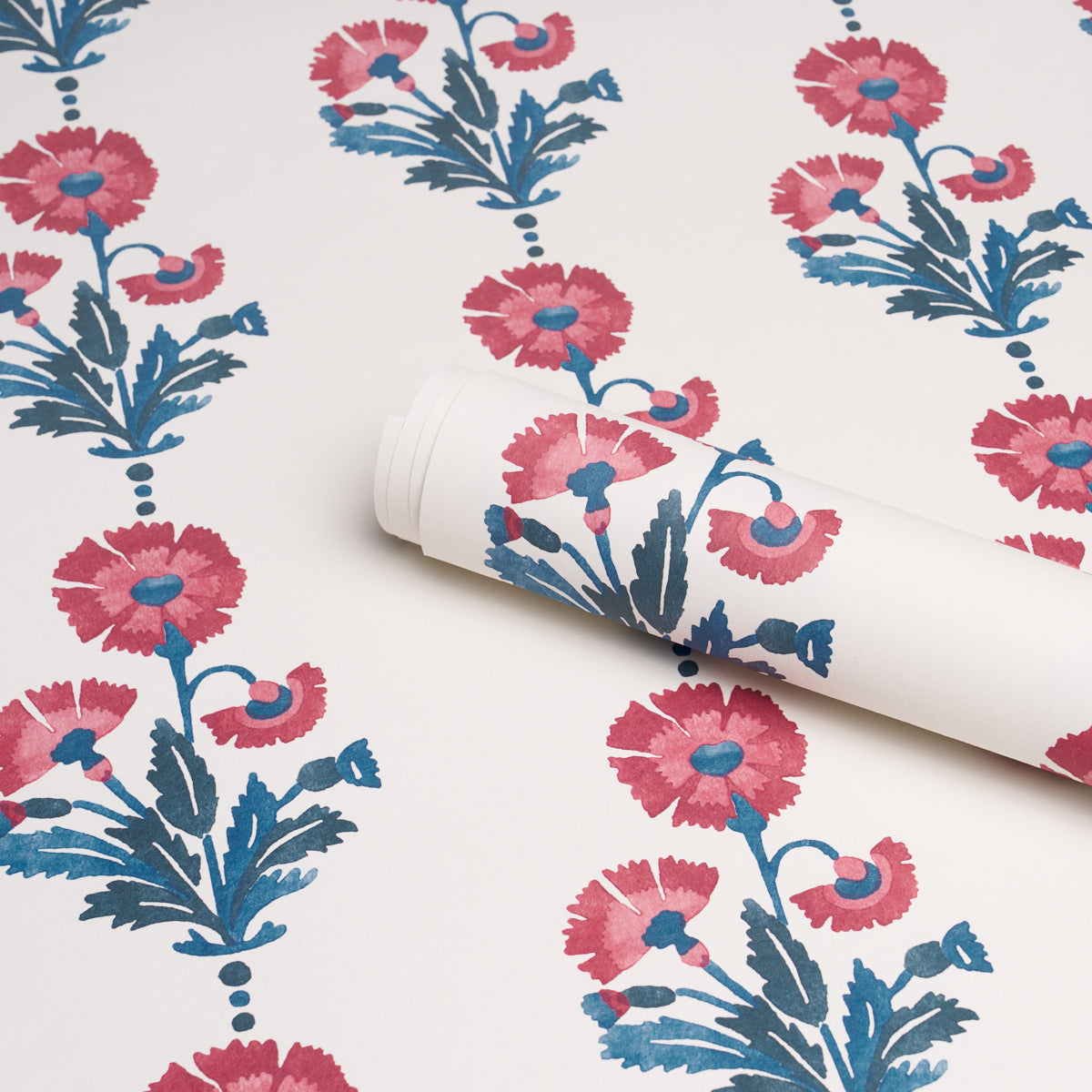 Roll of wallpaper featuring dianthus flowers in indigo tones with blue leaves against a white backdrop; bold botanical pattern.