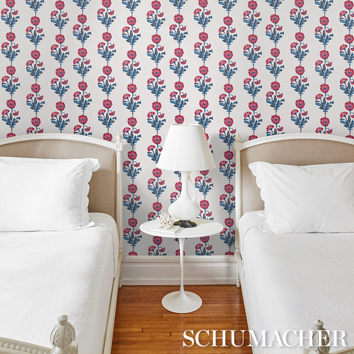 Wallpaper with pink-blue dianthus floral pattern in indigo tones on the wall behind a bedroom scene.