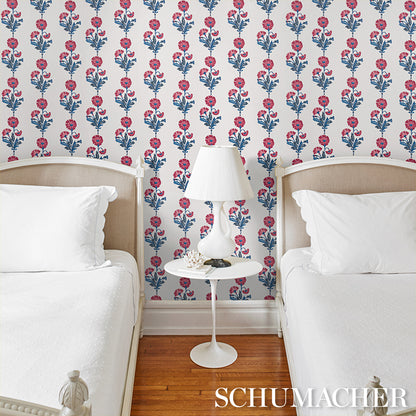 Wallpaper with pink-blue dianthus floral pattern in indigo tones on the wall behind a bedroom scene.