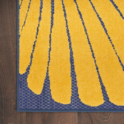 Yellow tufted rug with navy petal-like arches and navy border on dark wood floor.