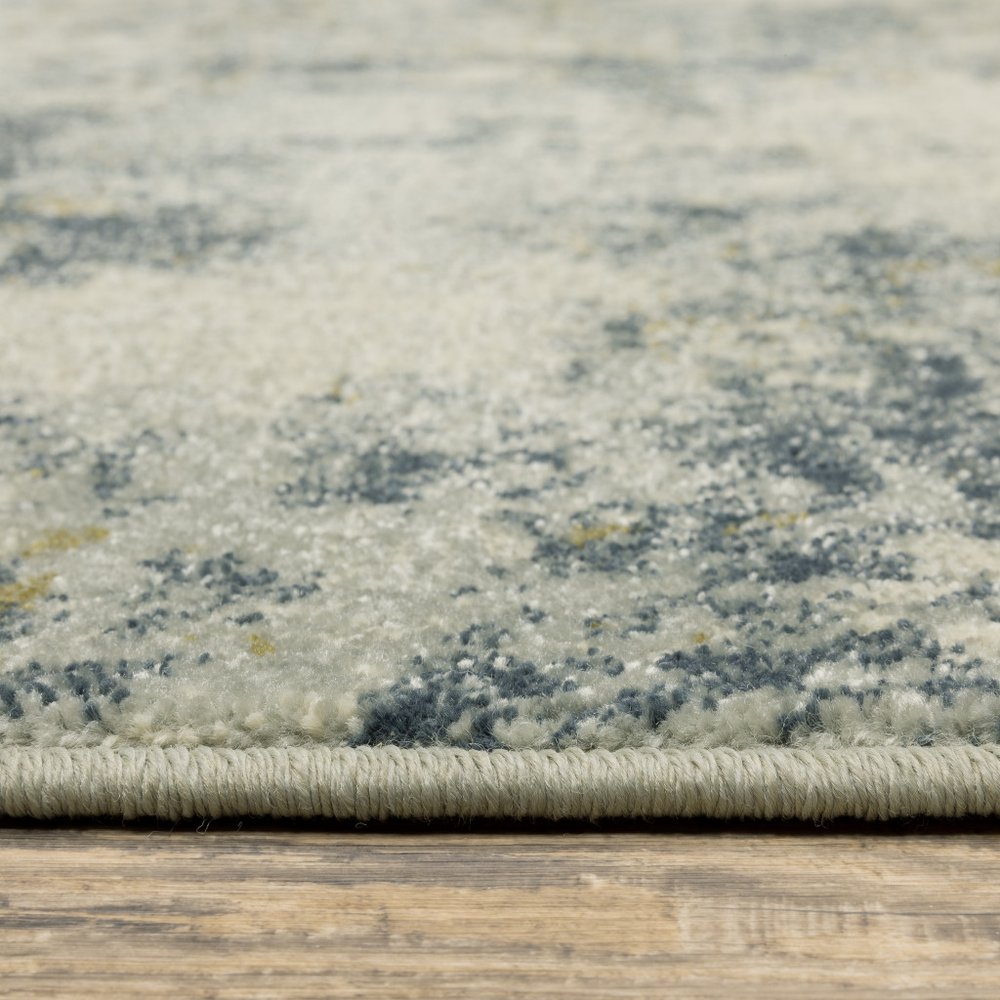 8' x 10' beige, teal, grey and gold abstract area rug on a wooden floor
