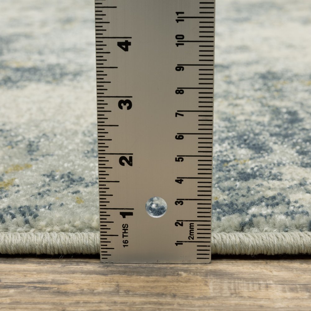 Stainless steel measuring ruler against a light gray patterned rug with beige fringe along the edge.