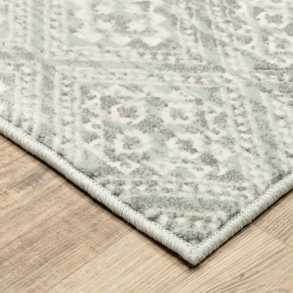 Gray and ivory geometric distressed area rug with a pale bound edge on a wooden floor.