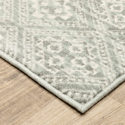 Gray and ivory geometric distressed area rug with a pale bound edge on a wooden floor.