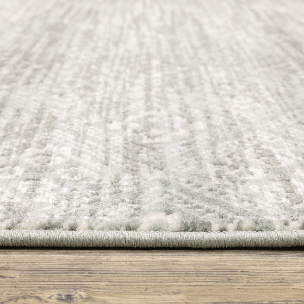 Gray and ivory patterned rug with soft pile and bound edge on a wood floor.