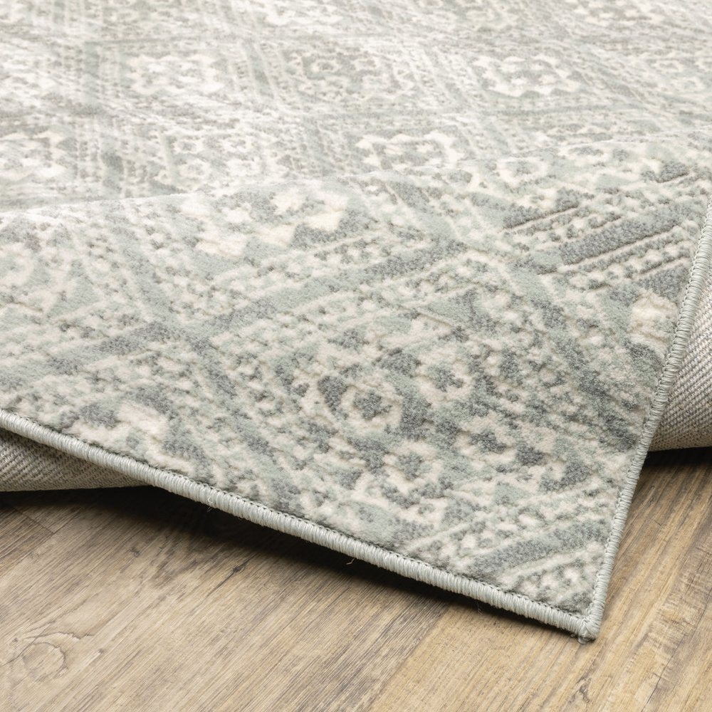 10' x 13' light gray and gray geometric distressed area rug with bound edge laid on wood floor