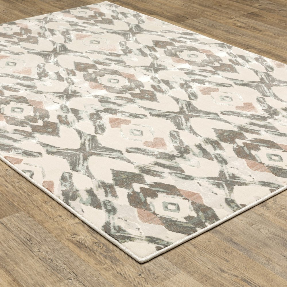 Ivory, pink and sage geometric area rug on a wooden floor.