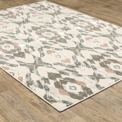 Ivory, pink and sage geometric area rug on a wooden floor.