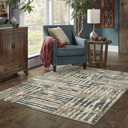 Rectangular beige-gray abstract area rug in a cozy living room with teal nailhead-armchair and wooden tables.