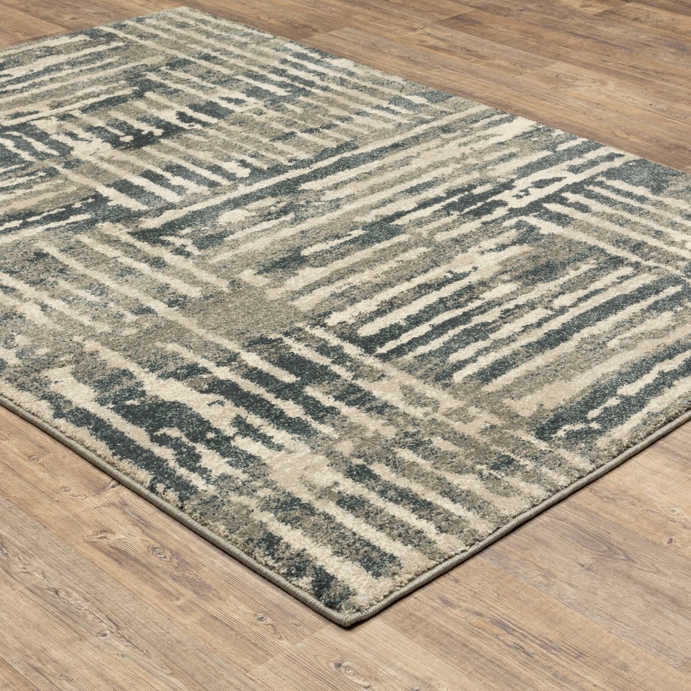 Abstract striped area rug in blue-gray and beige on wooden floor, contemporary style.