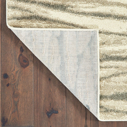 Beige textured area rug with wavy darker stripes, partially flipped at corner to reveal gray underside on dark wood floor.