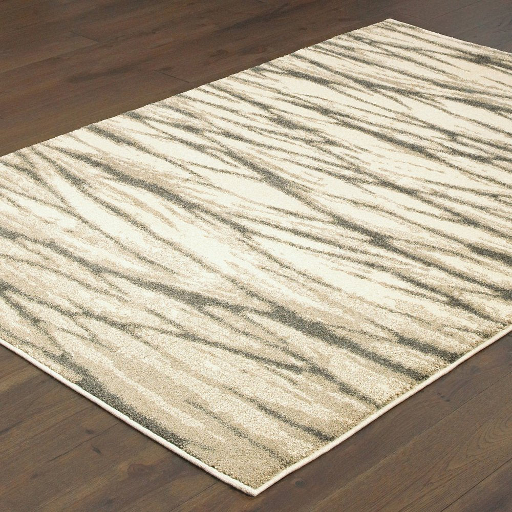Rectangular ivory and sand shag rug with an abstract pattern on dark wood floor.