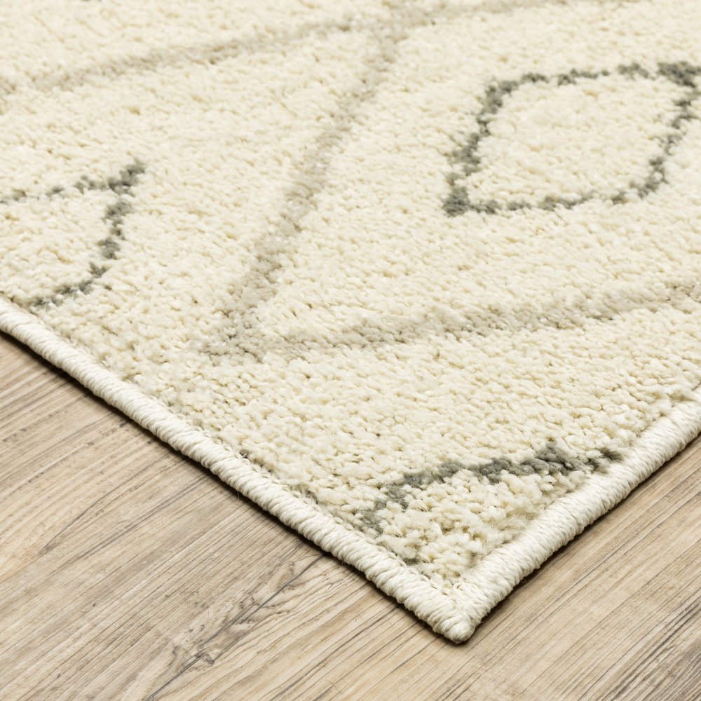 Cream textured rug with light gray geometric pattern on a light wood floor.