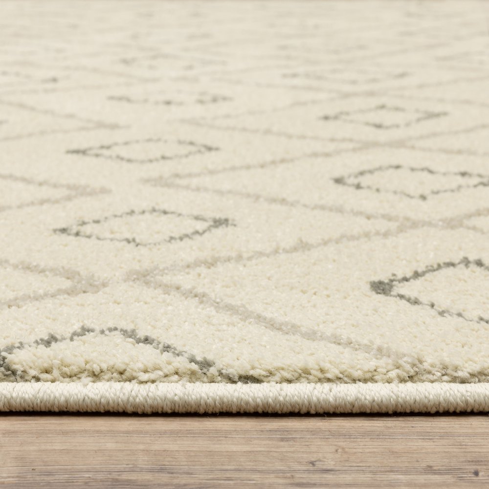 Cream rug with subtle gray diamond lattice pattern, low-pile, bound edge, on wood floor.