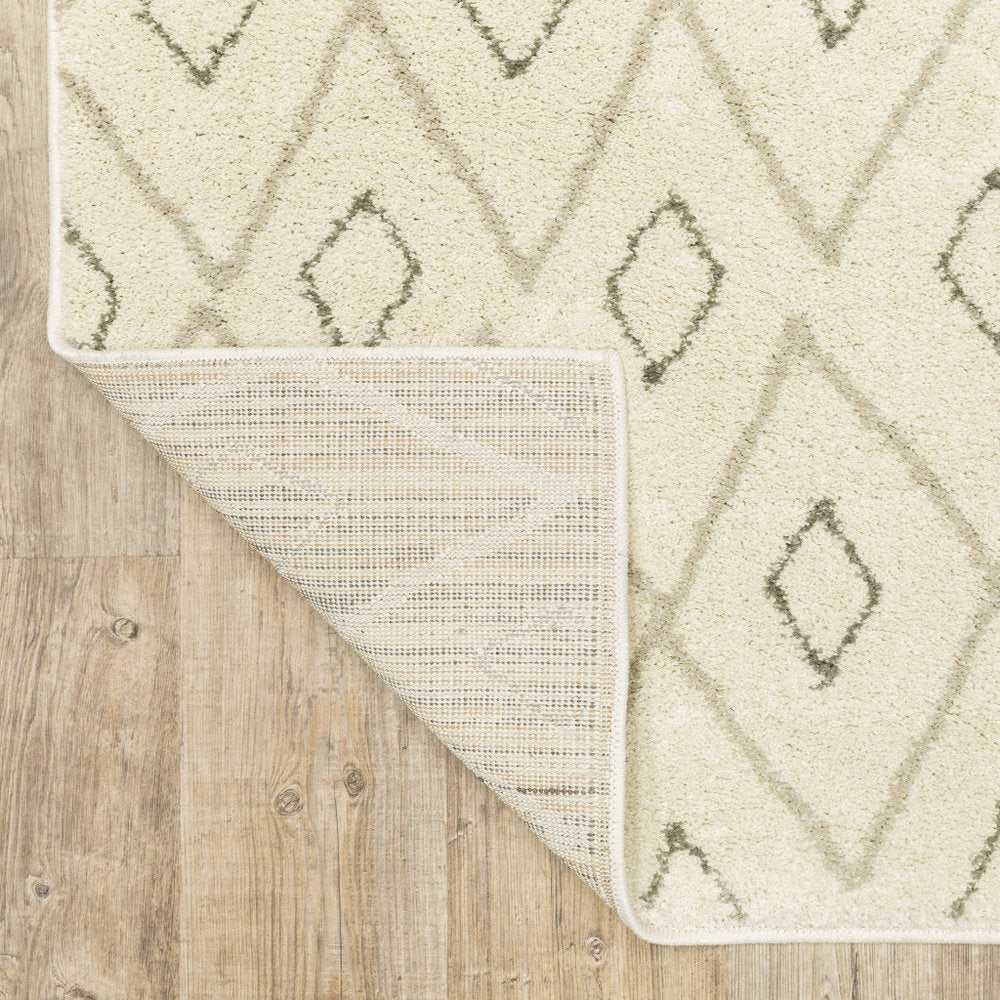 Cream rug with light gray diamond geometric pattern; folded corner shows woven underside on wood floor.