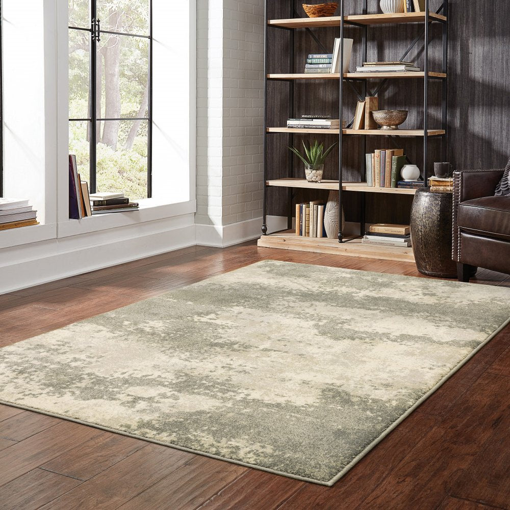 Rectangular beige and gray distressed abstract area rug on dark hardwood floor.