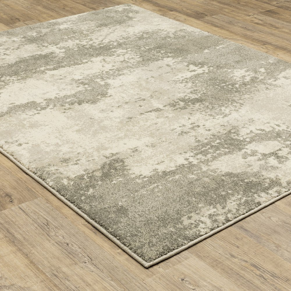 Abstract beige and gray low-pile area rug on wood floor, rectangular modern design.