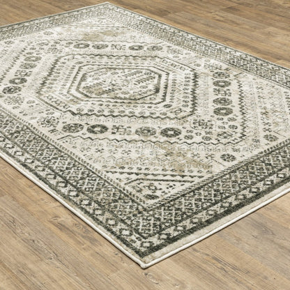 Distressed ivory and gray geometric rug with concentric octagonal medallions and ornate border on a wooden floor.