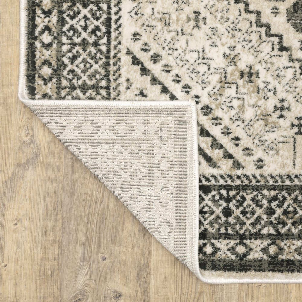 Beige and black oriental-style area rug with geometric patterns; folded corner reveals light underside.