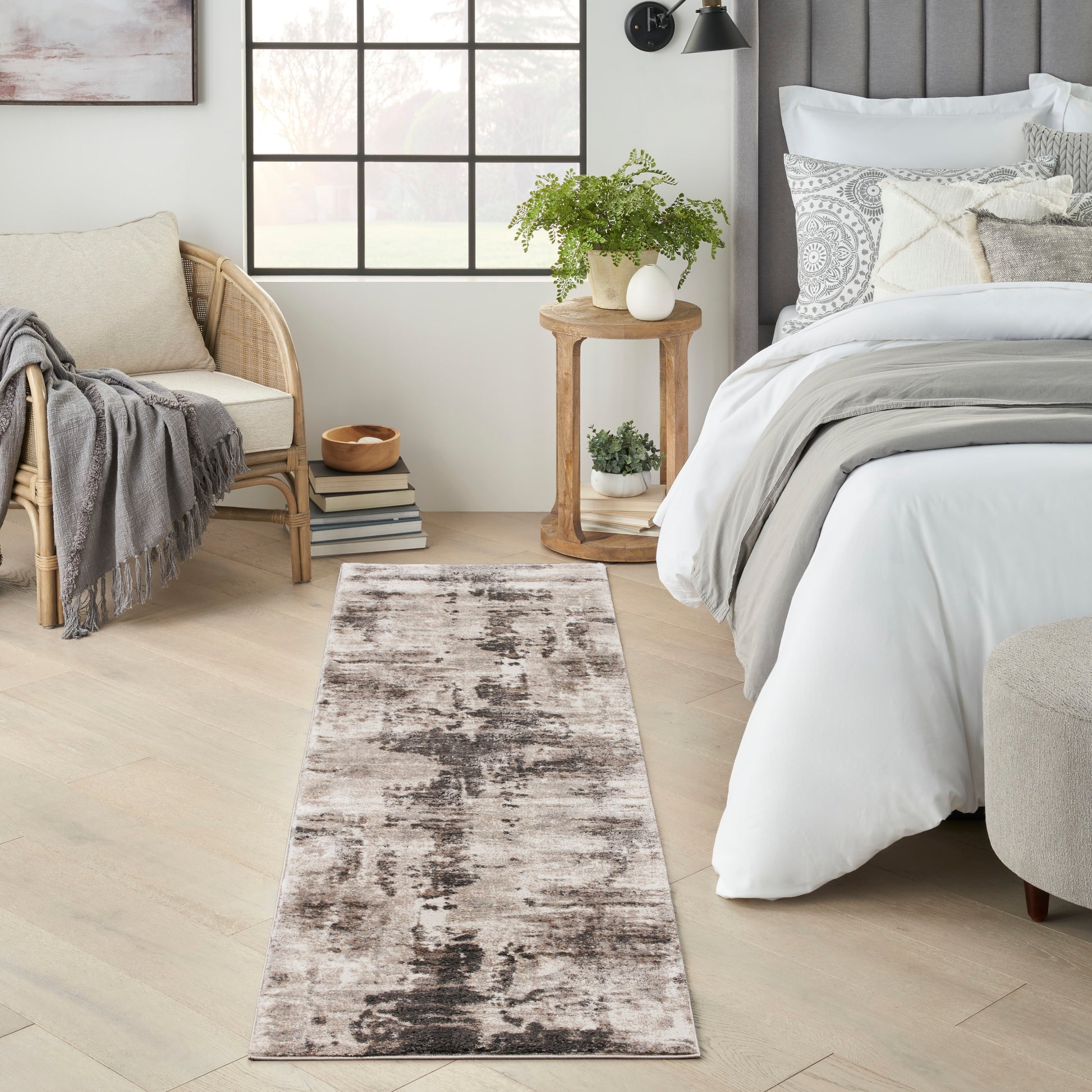 Long neutral runner rug with a distressed abstract pattern in beige, taupe and charcoal beside a bed in a modern bedroom.