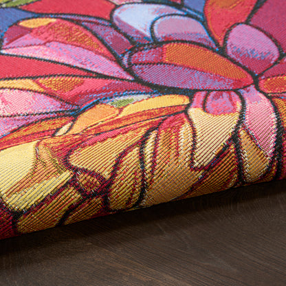 Bright floral woven textile with pink, orange, yellow and purple petals and bold black outlines, folded on wood.