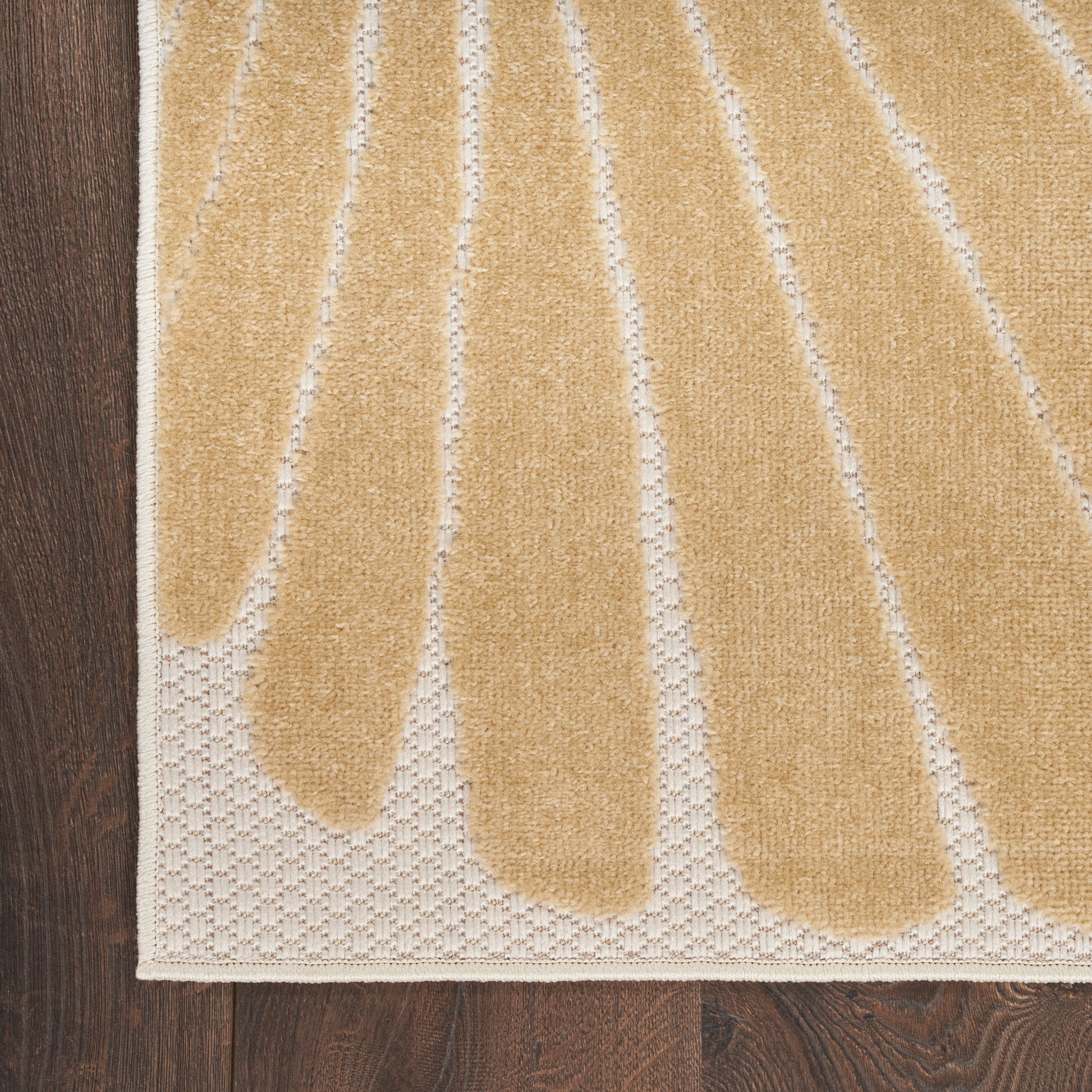 Beige woven rug with tan leaf shapes and a white border on dark wooden floor.