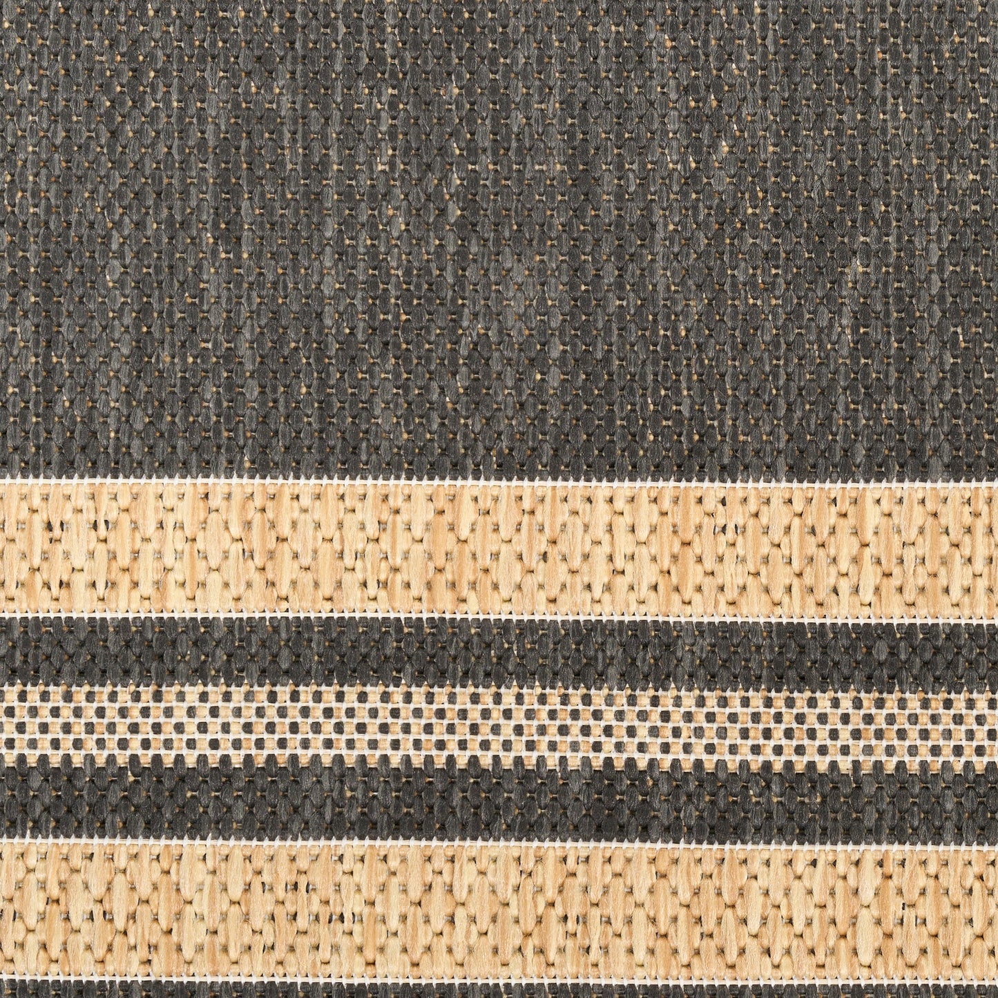 Close-up of a dark gray woven rug with beige horizontal stripes and dotted textures.
