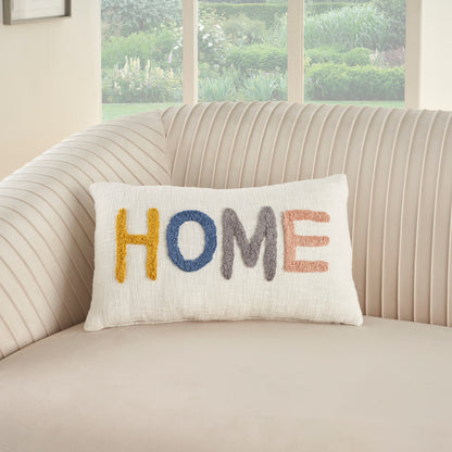 Beige striped sofa with a white textured pillow embroidered HOME in yellow, blue, gray and peach.