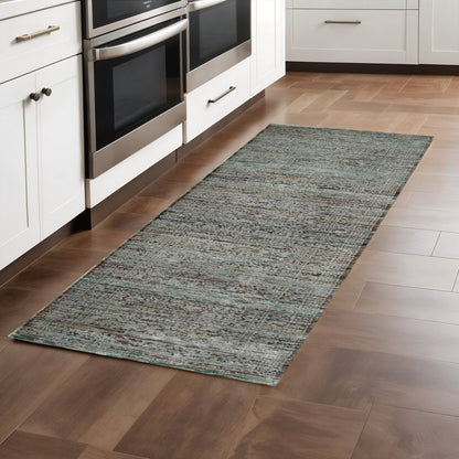 Blue & green oriental runner rug on brown wood kitchen floor beside white cabinets & stainless ovens.