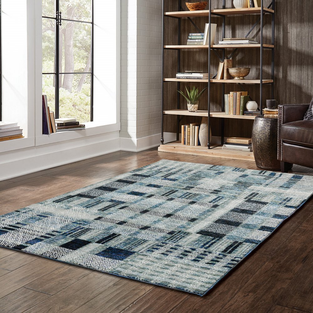Blue and gray abstract geometric area rug on dark wood floor in a modern living room.