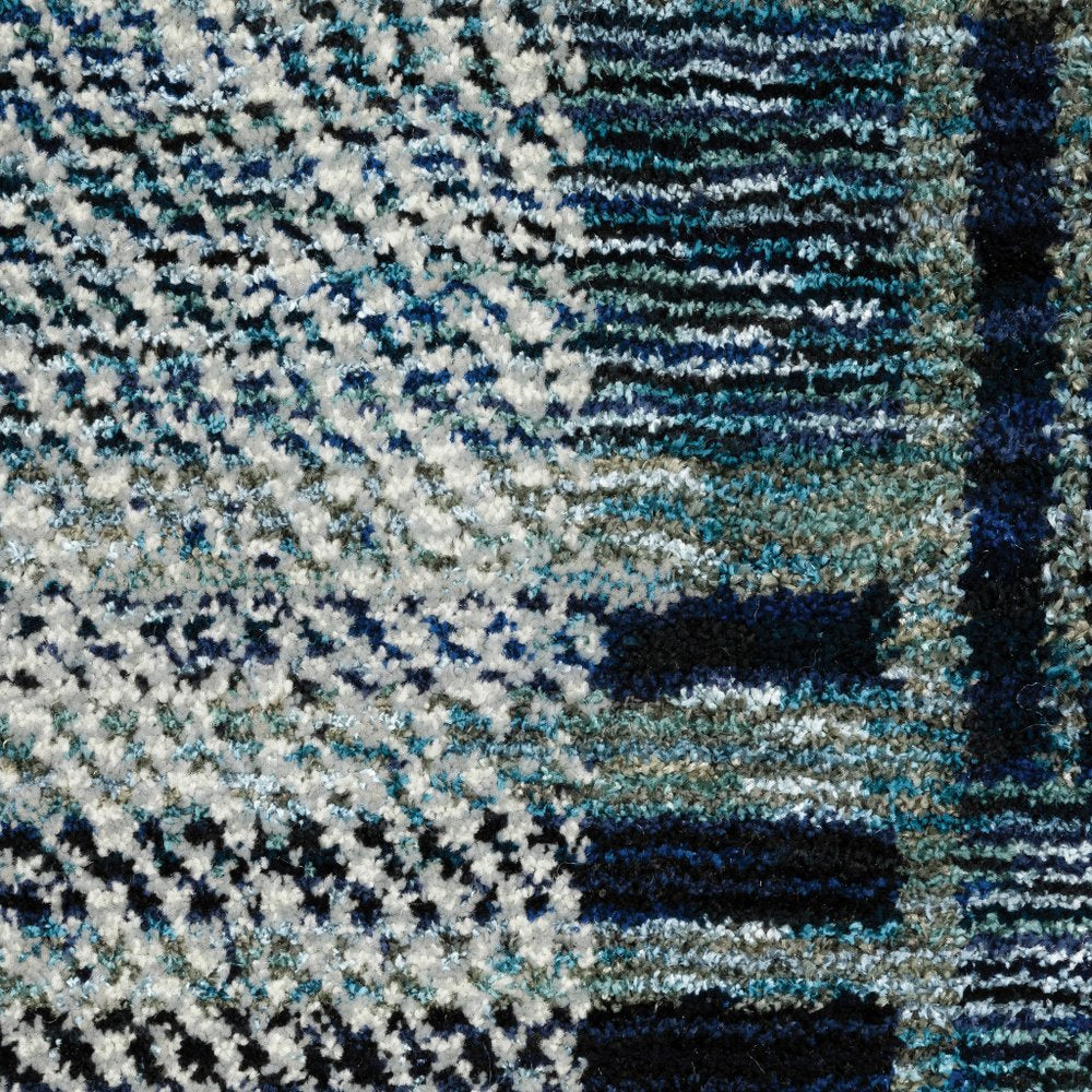 Close-up of a plush blue-teal white geometric area rug with dark navy accents.