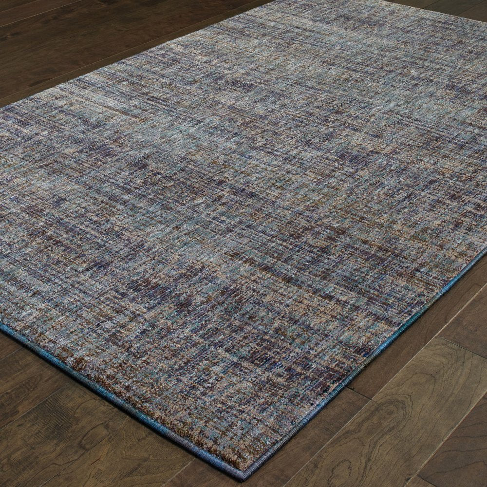 Rectangular blue and ivory abstract woven rug with blue edge and brown flecks on dark hardwood floor.